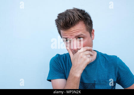 Portrait von zweifelhafter gutaussehenden Mann im casual blaues Hemd, mit unentschlossen Ausdruck auf seinem Gesicht Stockfoto