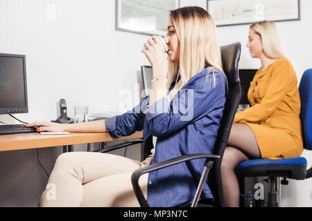 Freundliche Frauen arbeiten mit Computern im Büro. Zwei weibliche Kollegen am Schreibtisch sitzen und arbeiten. Stockfoto