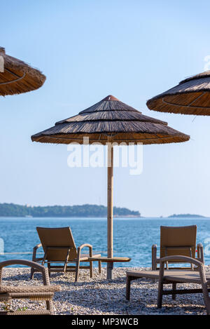 Reed Sonnenschirme und Liegestühle am Strand Stockfoto