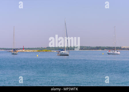 Yachten in der Bucht vor Anker, Segelboote, kleine Insel mit roter Leuchtturm im Hintergrund Stockfoto