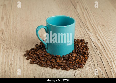 Körner von Kaffee auf einem hölzernen Hintergrund in großen Mengen und eine Schale Stockfoto