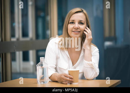Sportliche Frauen mit Smart Phone und trinken Kaffee im Coffee Shop. Stockfoto