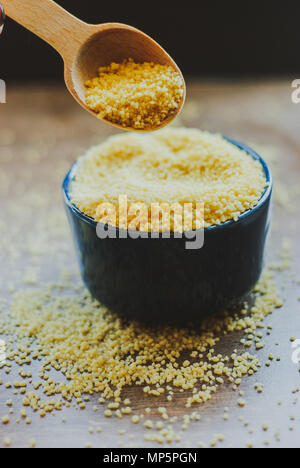 Rohes Couscous in die Schüssel auf Holz- Hintergrund Stockfoto