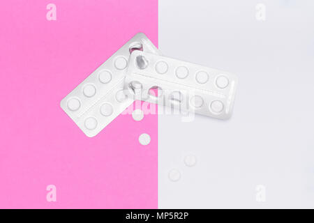 Weiße Pillen und Blisterpackung auf Rosa pastellfarbenen Hintergrund. Pharmazeutische Industrie minimal noch Leben flach Hintergrund. Opioid-Epidemie. Stockfoto