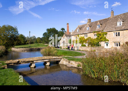 Lower Slaughter, Großbritannien - 7. Oktober 2010: Touristen im Herbst Sonnenschein auf der idyllischen Cotswold stone Riverside Cottages von Lower Slaughter. Dieses malerische Dorf auf dem Auge stream ist bekannt für seine unberührten Kalkstein Cottages in der traditionellen Cotswold Stil bekannt. Die idyllische Cotswold stone Riverside Cottages von Lower Slaughter im Herbst Sonnenschein, Gloucestershire, VEREINIGTES KÖNIGREICH Stockfoto