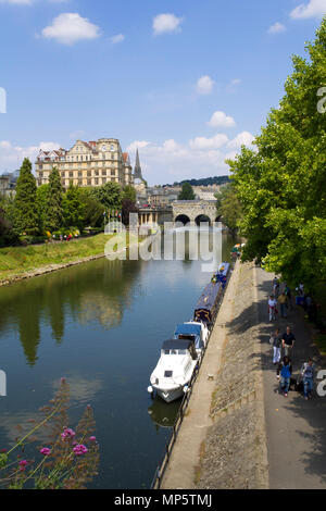 Bath, Großbritannien - 3.. Juli 2011: Frauen sitzen in der Sommersonne neben den bunten Kanalbooten, die auf dem Fluss Avon in der Nähe des Stadtzentrums von Bath, Somerset, Großbritannien, festgemacht sind. Bath ist ein UNESCO-Weltkulturerbe und berühmt für seine Architektur. Stockfoto