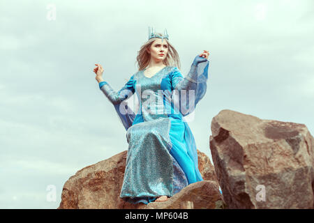 Schöne elf Frau im blauen Kleid sitzt auf einem Stein. Stockfoto