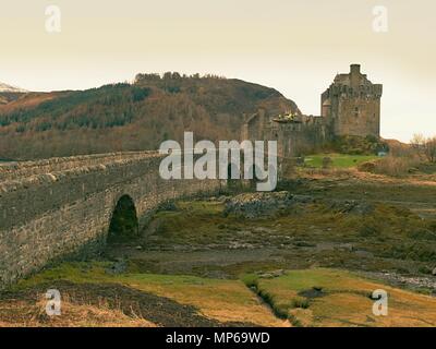 Schöne Dämmerung über Loch an Eilean Donan Castle in Schottland, niedriger Wasserstand Balg steinerne Brücke. Stockfoto