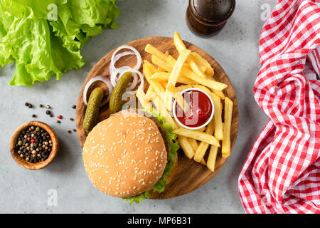 Burger mit Sesam, Pommes, Gurken und Kopfsalat. Blick von oben auf die hausgemachte Beef Burger mit Pommes und Pickles. Horizontale Stockfoto