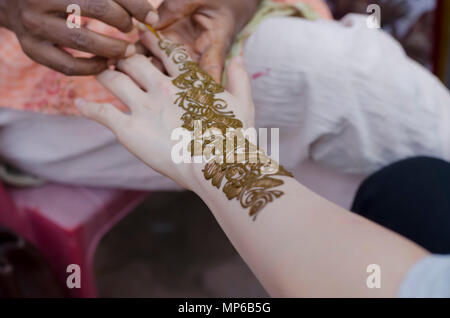 Eine henna Artist an Shilparamam Kunst und Handwerk Dorf, Hyderabad, Indien, Anwendung mehndi Paste auf die Hand einer Frau. Kunst und Vielfalt. Stockfoto