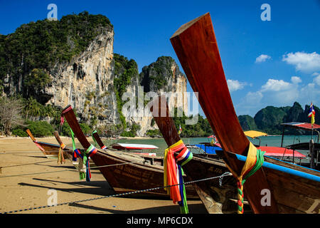 Long tail Boote mit karst Klippen und blauen Himmel im Hintergrund in West Railay, Tonsai, Strand, Thailand Stockfoto