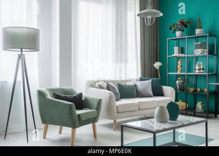 Lampe neben einem grünen Sessel und beige Sofa im Wohnzimmer Interieur und Dekoration auf dem Tisch Stockfoto