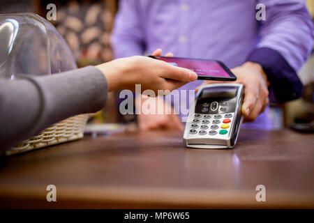 Bild des Verkäufers mit Terminal und Käufer mit Smartphone in Store Stockfoto