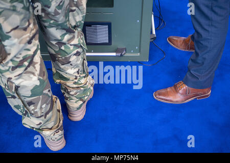 15. Mai 2018, Deutschland, Stuttgart: ein Mann in der militärischen Hosen und ein Mann im Anzug nebeneinander stehen während der ITEC-Messe für Militär und Waffen Technik. Foto: Sebastian Gollnow/dpa Stockfoto