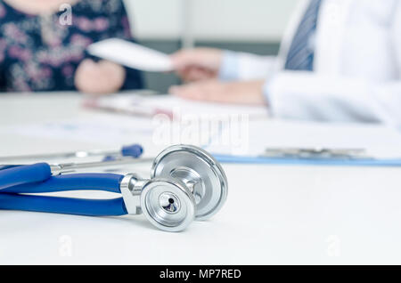 Stethoskop hautnah. Patient und Arzt im Büro. Arzt verordnet das Rezept im Hintergrund Stockfoto