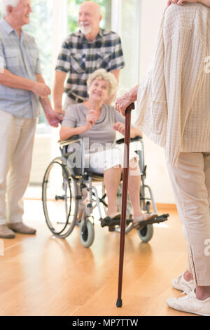 Ältere Person mit einem Spazierstock bei Treffen mit Freunden in der Krankenpflege Haus Stockfoto