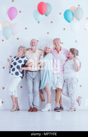 Gruppe begeisterter älterer Freunde mit bunten Luftballons feiert Geburtstag Stockfoto