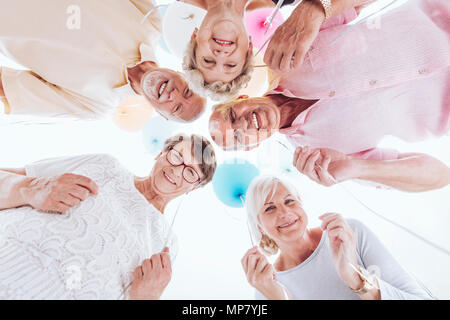 Niedrigen Winkel der älteren Freunde im Kreis stehend, Zusammen Spass haben während einer Konferenz Stockfoto