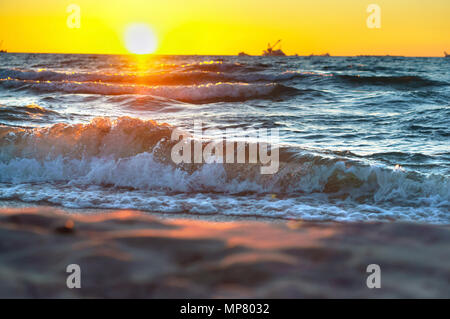 Sonnenuntergang über dem Meer. Reflexion des Sonnenlichts in den Meereswellen. Roter Himmel in den Strahlen des Sonnenuntergangs. Stockfoto