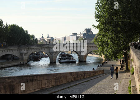 Touristenboot, das unter Pont Neuf vorbeifährt Blick auf die Brücke und Menschen, die am Kai entlang des linken Seineufers in Paris spazieren gehen, Frankreich KATHY DEWITT Stockfoto