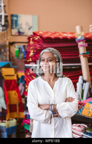 Reifen Stoff shop besitzer stehen unter ihrem farbenfrohen Textilien Stockfoto
