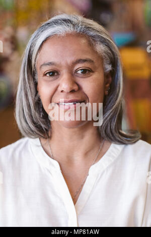 Lächelnd, reife Frau, die in ihrer farbenfrohen Kleidung Store Stockfoto