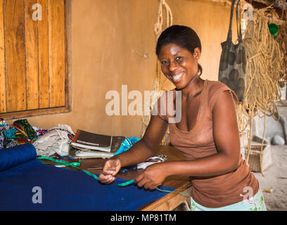 Lächelnd lokale afrikanische Frau arbeiten messen Tuch an Katundu kreative Handel Werkstatt, Likoma Island, Lake Malawi, Malawi, Süd-afrika Stockfoto