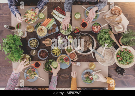 Verschiedene vegetarische Gerichte liegen auf Holztisch, Ansicht von oben Stockfoto