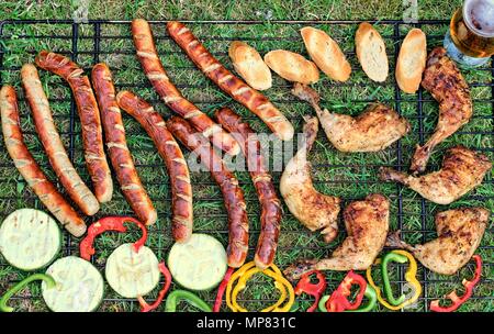 Leckeres Essen, Ernährung, kulinarischen und Grill Konzept: Close-up vom Grill Gitter mit Hähnchen Schenkel, Wurst, Gemüse und Baguette auf einem backgroun Stockfoto