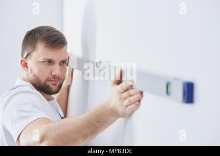 Männliche Spezialist für Home Renovierung Kontrolle der Wand mit Wasserwaage Stockfoto