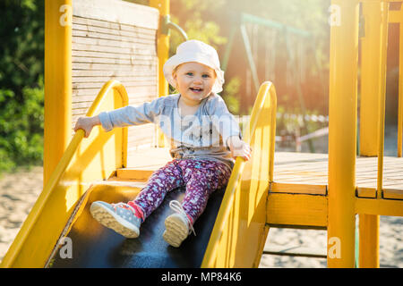 Glücklich lächelnde Kind auf Schieberegler am Spielplatz im Freien Stockfoto