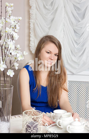 Lächelnd schöne Mädchen im Kleid sitzt am Tisch im gemütlichen Cafe. Stockfoto