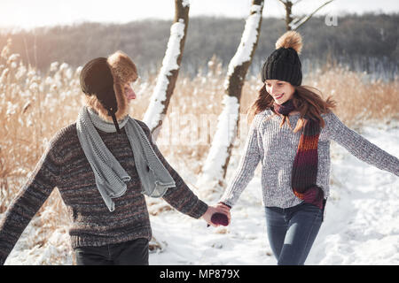 Paar hat Spaß und lacht. Kuss. Junge hipster Paar umarmen in Winter Park. Winter Love Story, eine schöne stilvolle junges Paar. Winter Fashion Concept mit Freund und Freundin Stockfoto