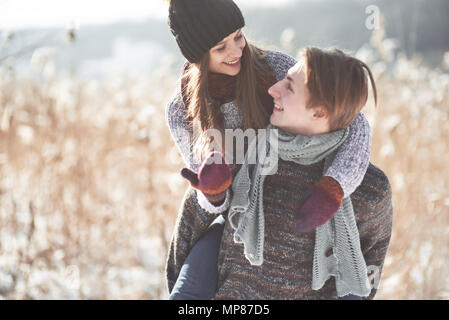 Paar hat Spaß und lacht. Kuss. Junge hipster Paar umarmen in Winter Park. Winter Love Story, eine schöne stilvolle junges Paar. Winter Fashion Concept mit Freund und Freundin Stockfoto