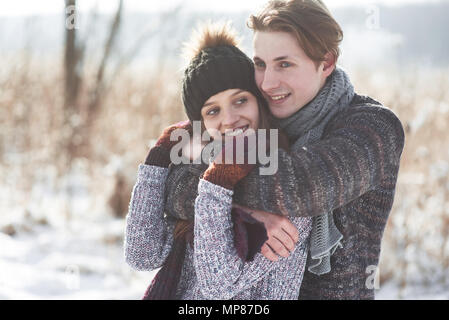 Paar hat Spaß und lacht. Kuss. Junge hipster Paar umarmen in Winter Park. Winter Love Story, eine schöne stilvolle junges Paar. Winter Fashion Concept mit Freund und Freundin Stockfoto