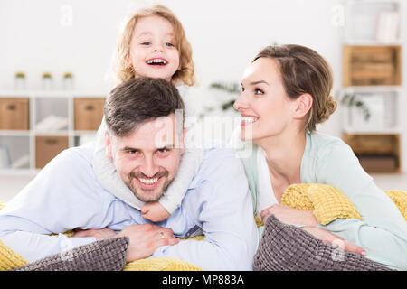 Lebendige Porträt einer Familie mit einem Kind lachen, Spaß unter grossen Kissen Stockfoto