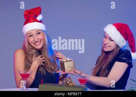 Freundinnen in Weihnachten Hüte mit Cocktails feiern das neue Jahr Stockfoto