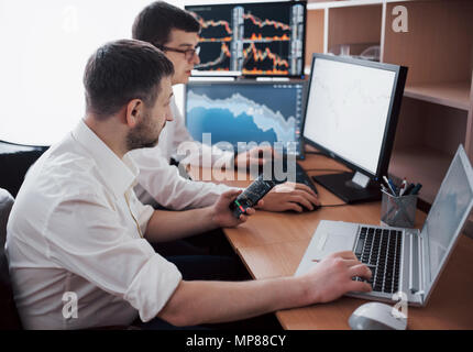 Unternehmer trading Stocks online. Börsenmakler, Diagramme, Indizes und Zahlen auf mehreren Bildschirmen. Die Kollegen in der Diskussion im Traders Büro. Geschäftlicher Erfolg Konzept Stockfoto