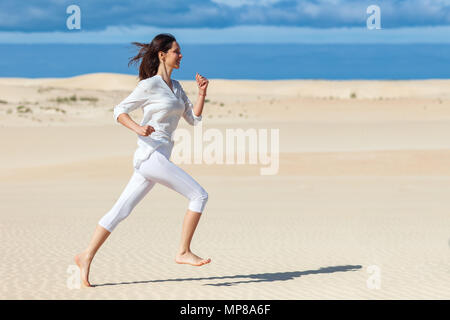 Schöne Mädchen in Sportkleidung in der Wüste. Seitenansicht der aktiven sportliche junge Frau, die auf Sand. Foto mit Kopie Raum Stockfoto