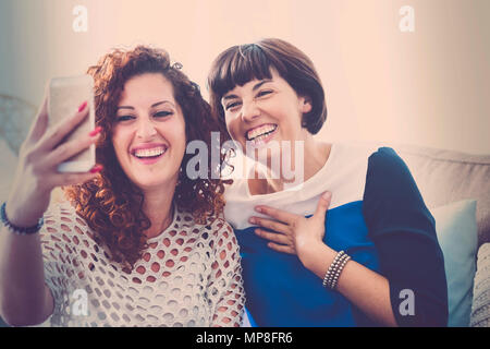 Rufen sie Freunde mit Handy in Live Video für ein paar schöne Mittlere Alter Frauen zu Hause. Kommunizieren und moderne Verbunden Personen Konzept. Stockfoto