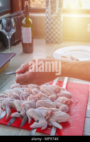 Eine Hand Stücke von marinierten Hähnchen am Spieß in der Küche an einem sonnigen Tag. Die vertikale Rahmen. Stockfoto