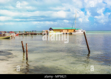 Caye Caulker, Belize - Dezember 24, 2016: Hölzerne Seebrücke Dock mit Touristen, Boote und malerischen, entspannende ocean view auf Caye Caulker Belize Karibik. Stockfoto