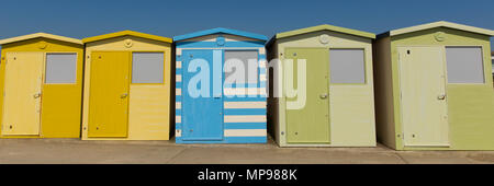 Umkleidekabinen am Strand in einer Reihe mit grünen blauen und gelben Farben und blauer Himmel Panoramaaussicht Stockfoto