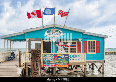 Caye Caulker, Belize - Dezember 20, 2016: Hölzerne Seebrücke Dock mit Gebäude und malerischen, entspannende ocean view auf Caye Caulker Belize Karibik. Stockfoto