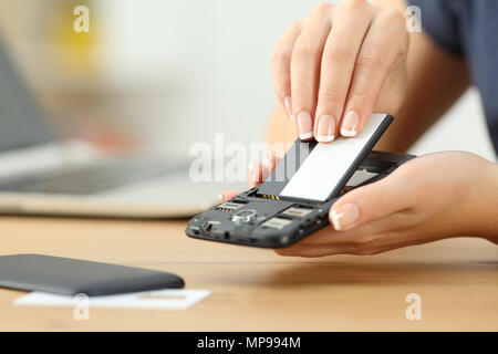 Nahaufnahme einer Frau Hand ein Akku in ein smart phone Stockfoto