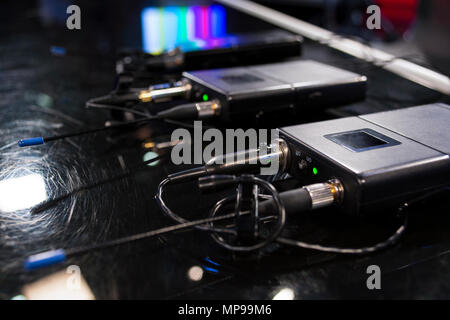 Drei drahtlose Mikrofone drahtlose Mikrofone Sender und drei Empfänger auf Schwarzen Tisch im TV-Studio Stockfoto