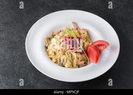 Italienisches Paste der Carbonaria mit Pilzen mit Sahnesauce auf einem weißen Teller. Stockfoto