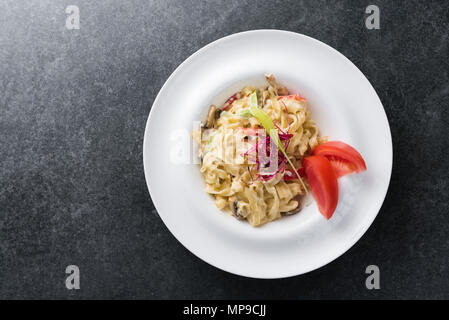 Italienisches Paste der Carbonaria mit Pilzen mit Sahnesauce auf einem weißen Teller. Stockfoto