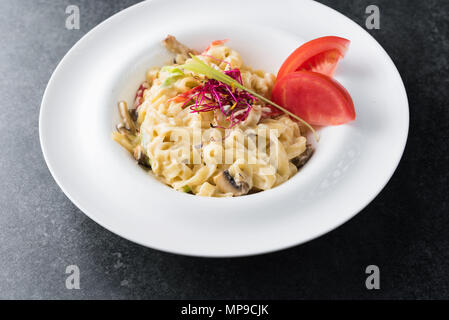 Italienisches Paste der Carbonaria mit Pilzen mit Sahnesauce auf einem weißen Teller. Stockfoto