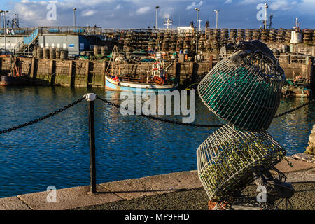 Lobster Pot Skulptur neben dem Hafen von Brixham, mit Fischerboot und echten Hummer Töpfe im Hintergrund. Brixham, Devon. März 2018. Stockfoto